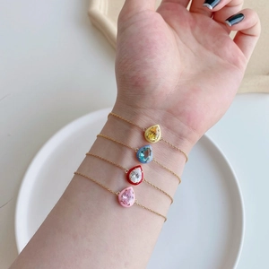 Detail of four golden S925 silver bracelets with colorful enamel and zircon charms
