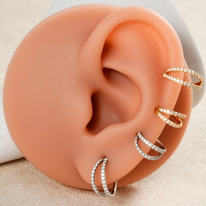 Detail view of triple-layered cubic zirconia nose rings worn on a silicone ear model