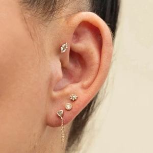 Macro shot of gold-plated brass stud earrings set with zircon stones on female ear