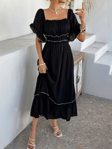 Detail of bohemian black dress showing square neck, smocked bodice, and white trim tier