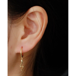 Close-up of gold S925 sterling silver snake earrings worn with small gemstone detail