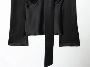 Detail of black satin shirt showing smooth silk texture and elegant tie-neck ribbon detail