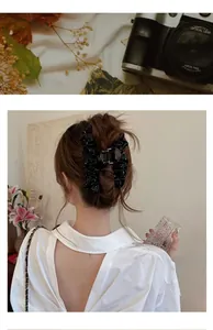 Détail d'une grande pince à cheveux en satin plissé noir ornée de perles fines