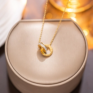 Rose gold Roman necklace with interlocking double rings and zircon on a beige jewelry box