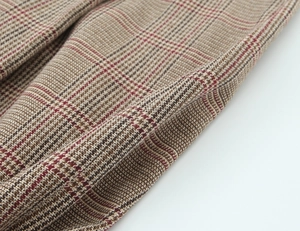 Macro shot of houndstooth plaid fabric detail in tan and burgundy wool texture
