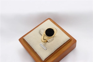 Close-up of a gold signet ring with a round black polished gemstone in a jewelry box