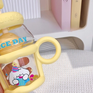 Detail view of the yellow glass cup featuring a round handle and a cartoon dog illustration