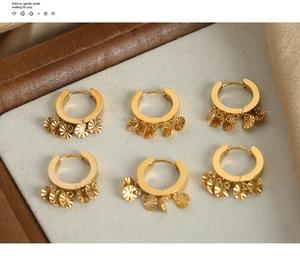 Détail de boucles d'oreilles en U dorées avec des pendentifs coquillages texturés