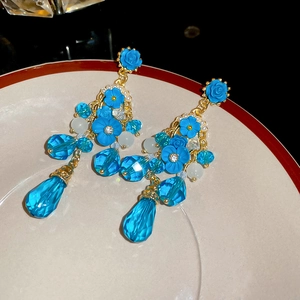 Détail de boucles d'oreilles fleur bleue avec cristaux et perles sur un plat céramique