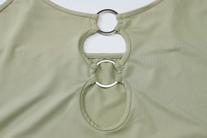 Detailed close-up of light green knit crop top with silver metal rings and cutout design