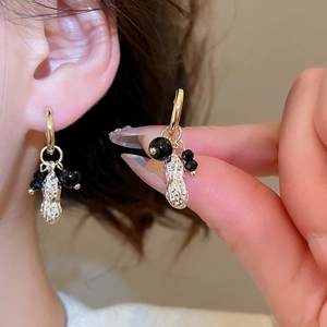 Detail of peanut pendant earring with black beads and gold hoop on ear model