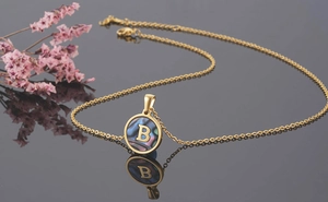 Macro shot of 18K gold plated necklace featuring a round shell pendant with letter B