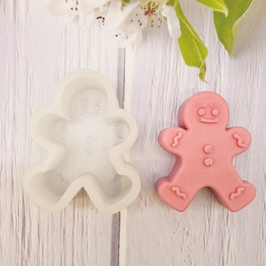 Silicone gingerbread man mold and pink handmade candle on white wooden background