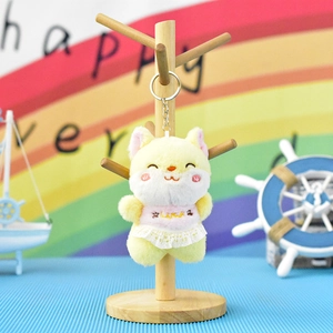 Detailed view of yellow plush cat keychain wearing lace dress on wooden stand