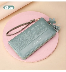 Detail of light blue crocodile embossed long wallet with tassel and wristlet strap