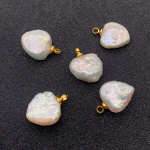 Macro shot of five natural white heart-shaped baroque pearl pendants with gold rings