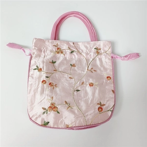 Detailed close-up of pink silk satin embroidery with floral patterns and drawstring closure
