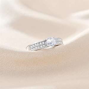 Macro detail of silver zirconia ring featuring four-prong setting on silk background