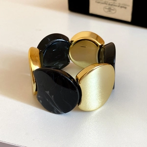 Macro detail of elastic chunky bracelet with gold metal and black marble resin links