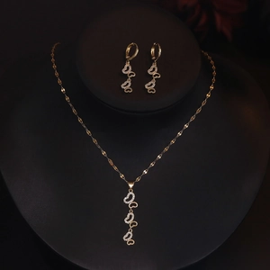 Golden heart pendant necklace and earrings set with zircons on a black neck display