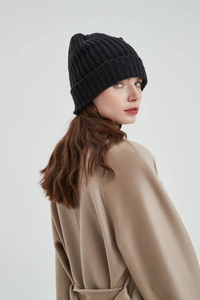 Close-up of black knit beanie texture paired with a beige wool coat for winter style