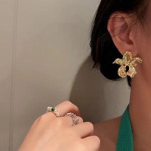 Detailed close-up of gold flower stud earrings with irregular vintage texture on model