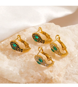 Détail de boucles d'oreilles serpent dorées avec yeux verts sur quartz blanc et soie
