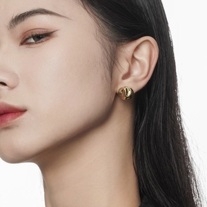 Irregular golden disc earrings in S925 sterling silver worn by a model in close-up