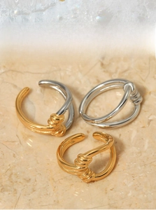 Macro shot of twisted knot ear cuffs in gold and silver finish with polished metal texture