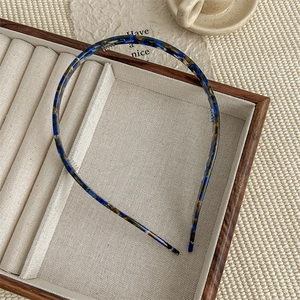 Detailed view of a tortoiseshell acetate headband in blue and brown on a wooden display