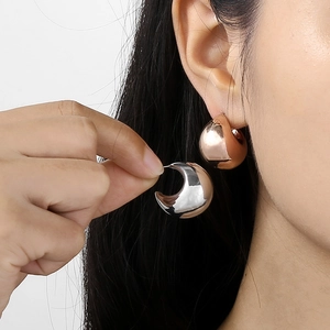 Detail of chunky hollow crescent hoop earrings in gold and silver finish on model