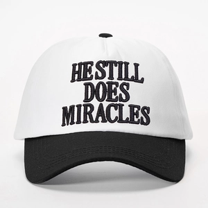 Classic black and white baseball cap with HE STILL DOES MIRACLES embroidery design