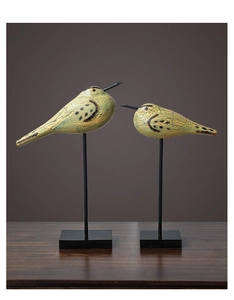 Détail de statues d'oiseaux nordiques en bois avec finition craquelée sur supports métalliques