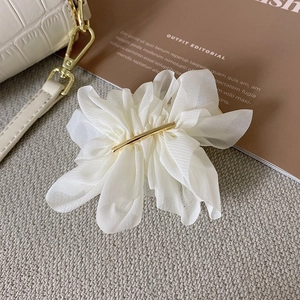 Détail de la pince à cheveux élégante en organza blanc avec barre en métal doré