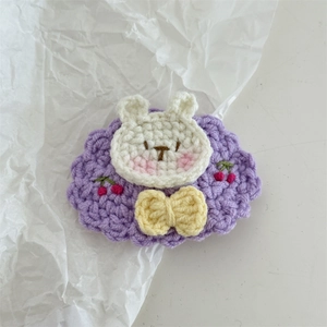 Handmade crochet bunny hair clip with purple floral base and yellow bow accessory