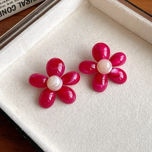 Close-up of magenta marble resin flower earrings with white bead center in a tray