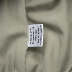 Detail view of the white satin care label on cotton linen dress with washing instructions