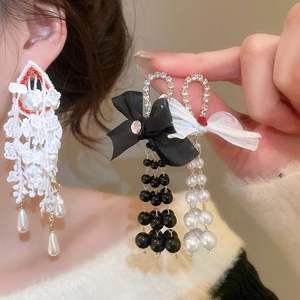 Detail of bow earrings with lace fringe, crystals and pearl charms on model