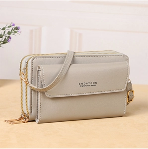 Close-up of triple-zipper storage compartments and gold hardware on grey crossbody bag
