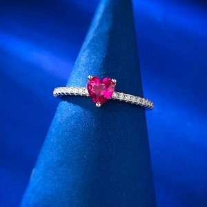 Macro detail of heart-shaped pink gemstone ring with diamond pavé on silver band