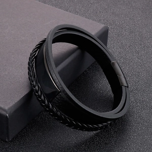 Close-up of triple-layer black woven leather bracelet with a sleek metal clasp on a box