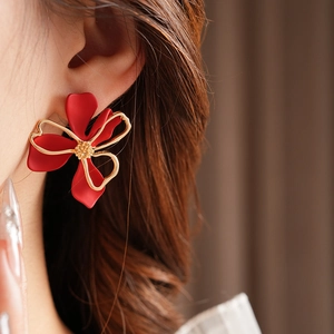 Close-up of a vintage red floral earring with gold metallic edges worn on the ear