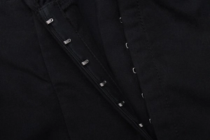 Detailed macro view of black fabric with metallic hook and eye closure on a fashion top