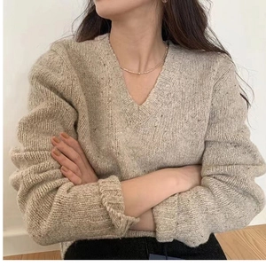 Détail du pull en maille à col en V couleur avoine avec des finitions aux poignets