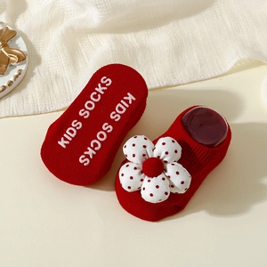 Detail of red infant floor socks featuring white floral accents and anti-slip grip soles