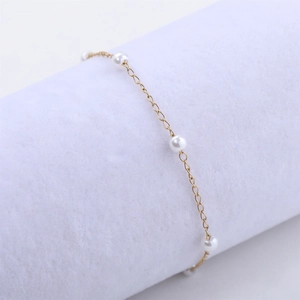 Détail du bracelet de perles 4mm en or 18 carats sur un support à bijoux en velours blanc