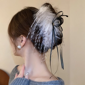Elegant hair claw clip with plush feathers and black silk ribbon on model hairstyle