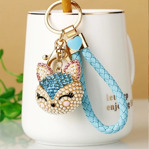 Detail of fox pendant keychain with blue beaded charms and woven lanyard on a mug