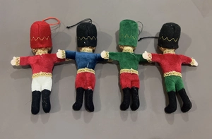 Flat lay of four colorful plush nutcracker soldier ornaments with detailed embroidery