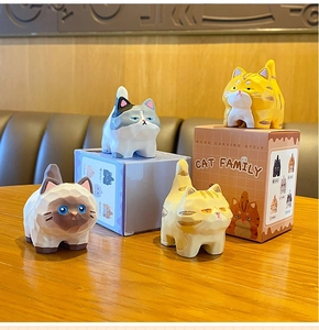 Close-up of four cat figurines in wood carving style with colorful cartoon gift boxes